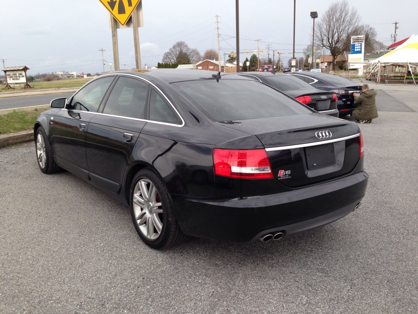 Rear side view of black sedan with quad exhaust and distinct taillights