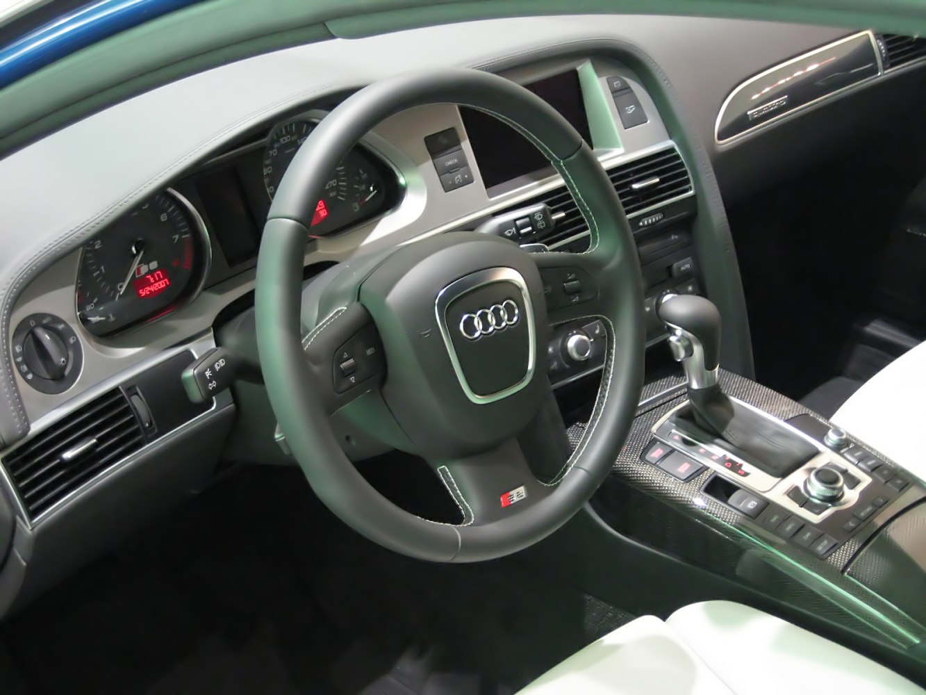 Luxury car interior with steering wheel, dashboard, and gearshift.