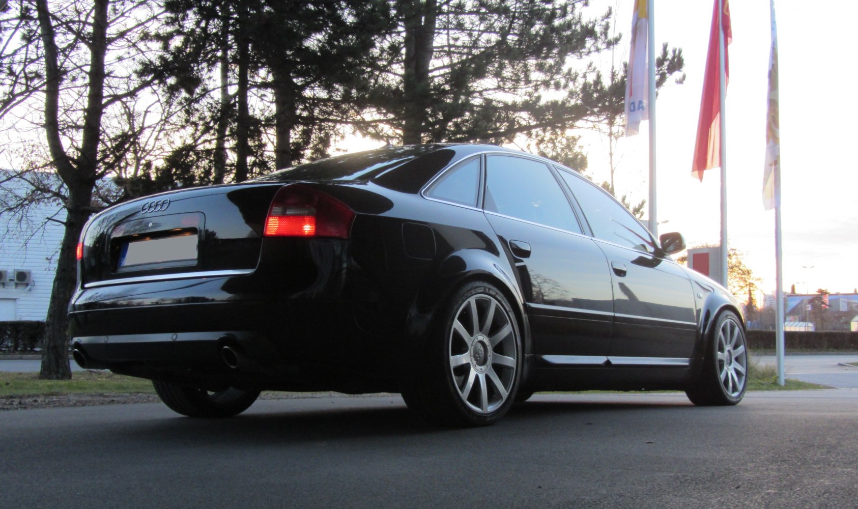 Black sporty sedan rear side with dual exhaust and alloy wheels