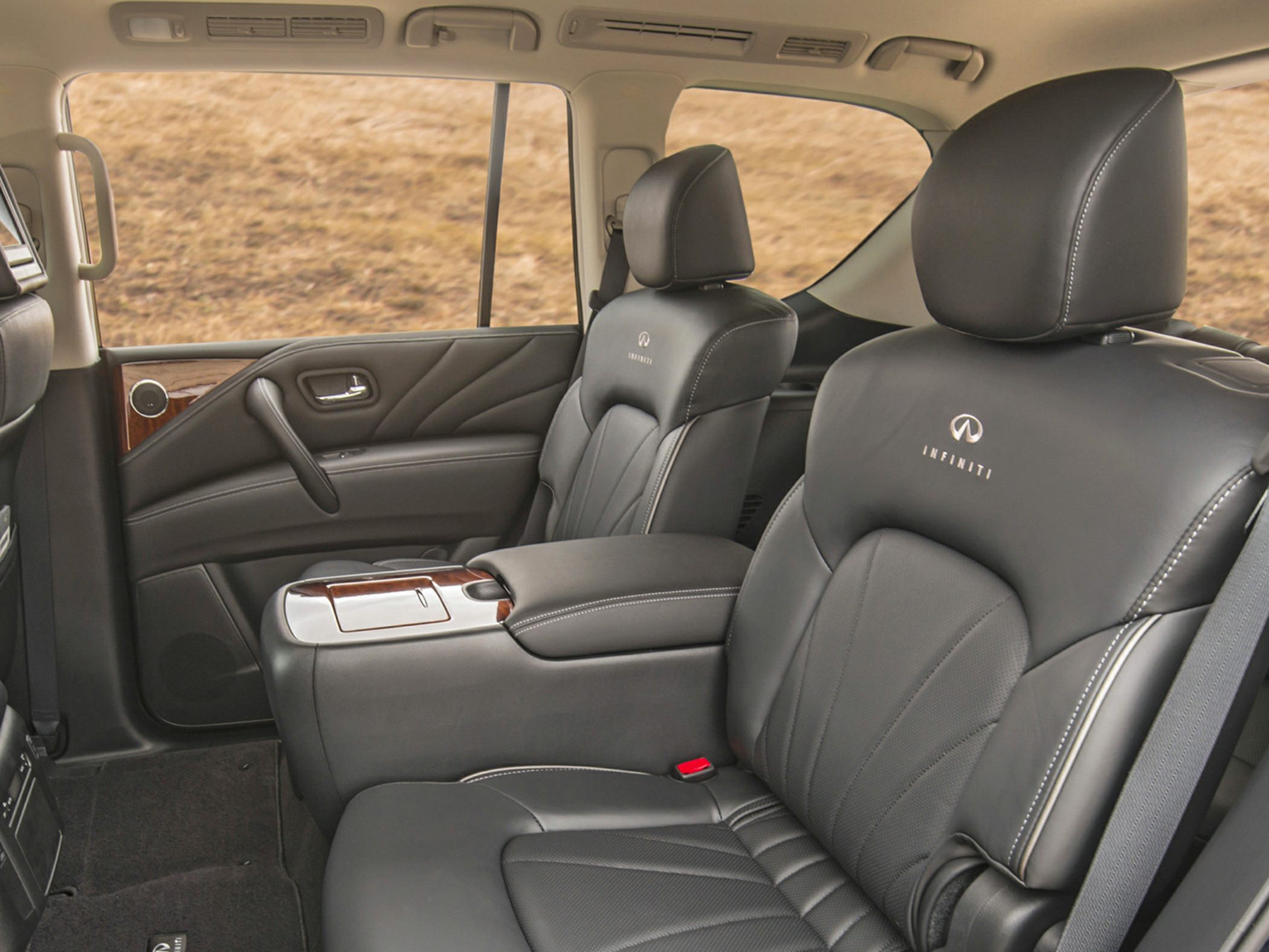 Black leather rear seats with white stitching and wood-trimmed armrest