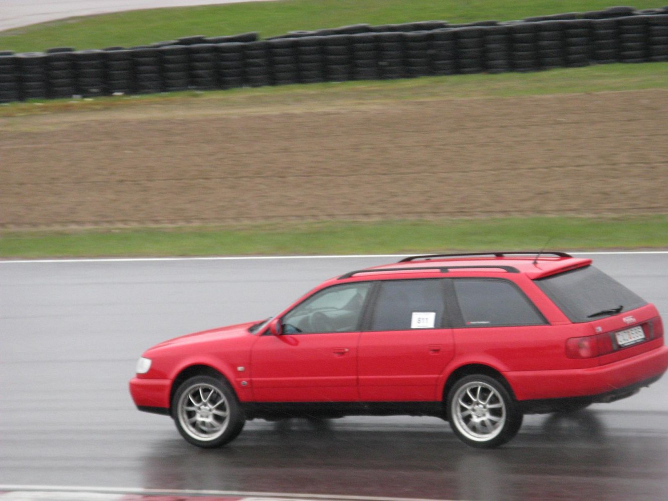 Red sporty estate with alloy wheels and roof rails on wet track
