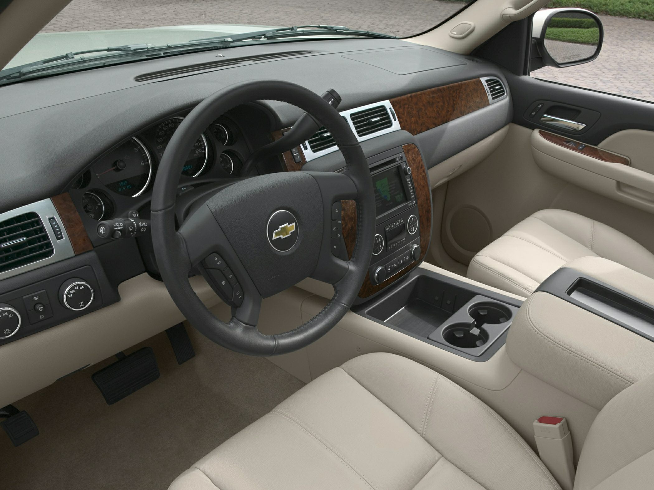 Dashboard with steering wheel, wood trim, and beige leather seats