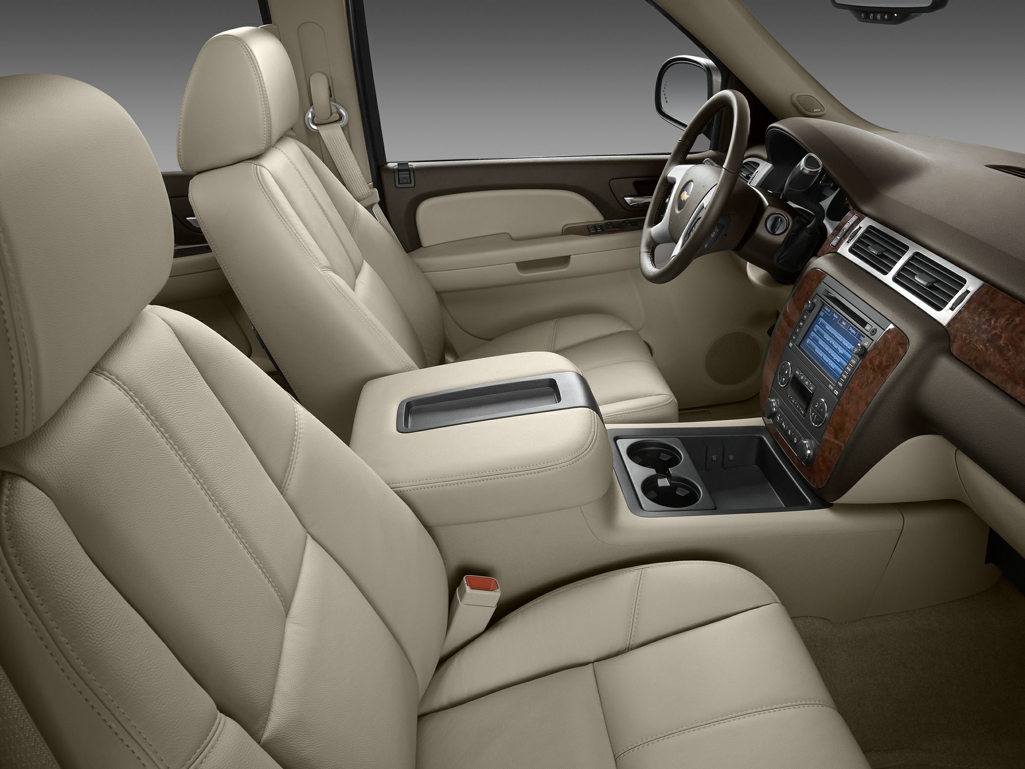 Beige leather interior with wood grain dashboard trim and center console cup holders.