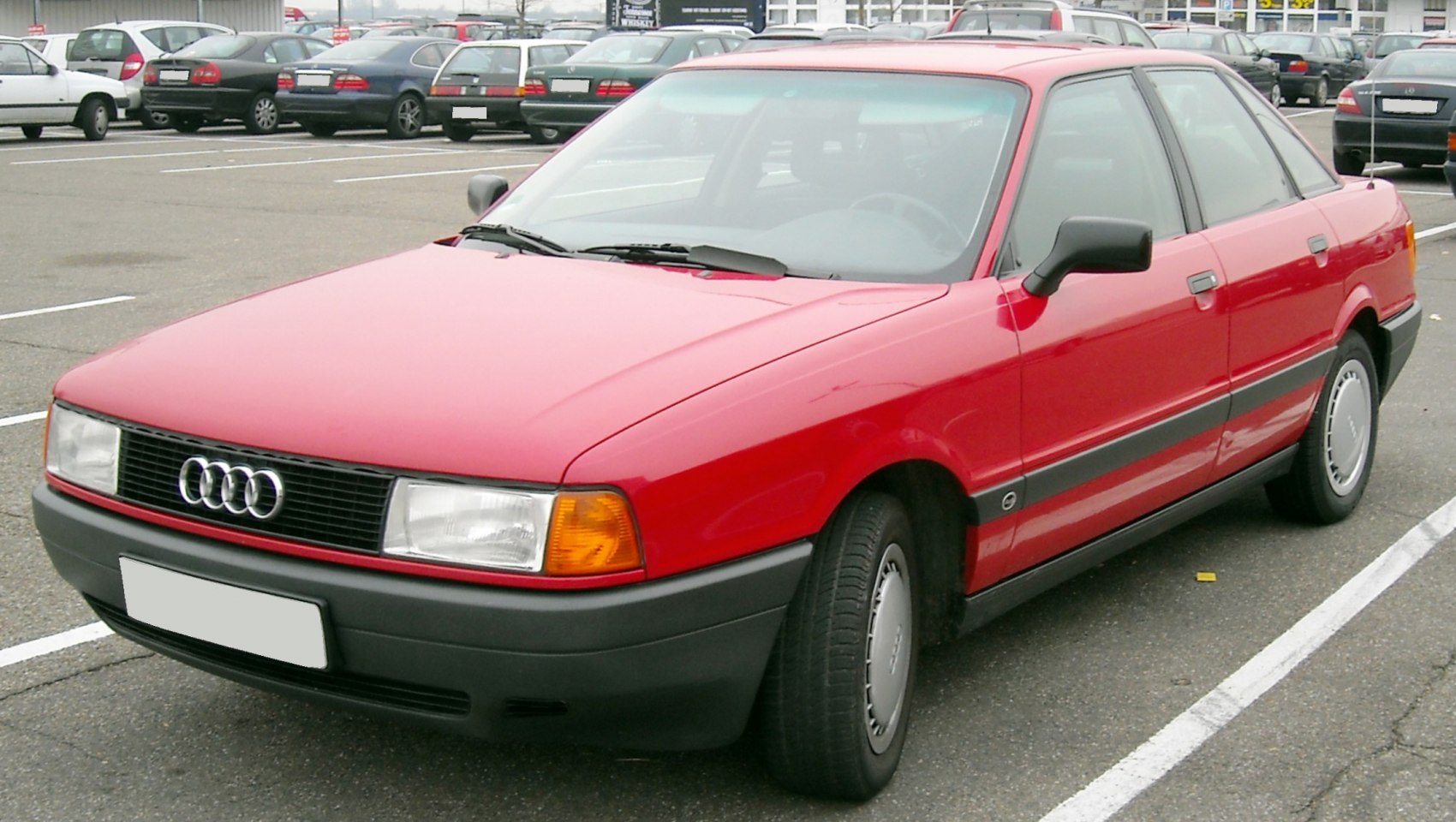 Red 1980s sedan with front-side angle and black trim details