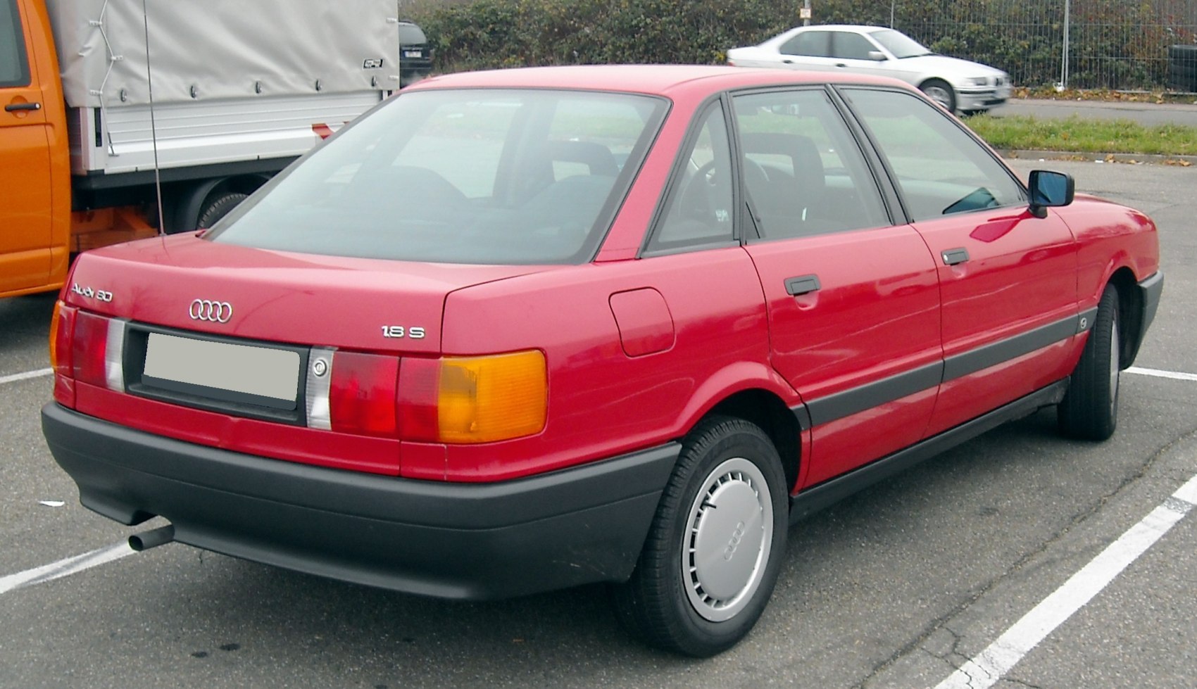 Rear view of a 1980s four-door sedan with integrated tail lights and black bumper trim.
