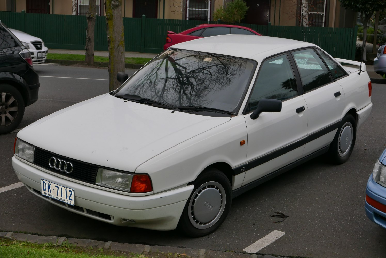 Boxy white four-door sedan with rear spoiler and classic hubcaps