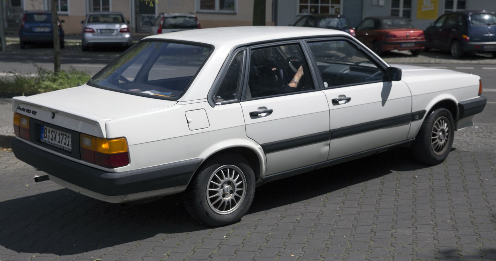 Rear-side view of classic 1980s sedan with alloy wheels and rear spoiler
