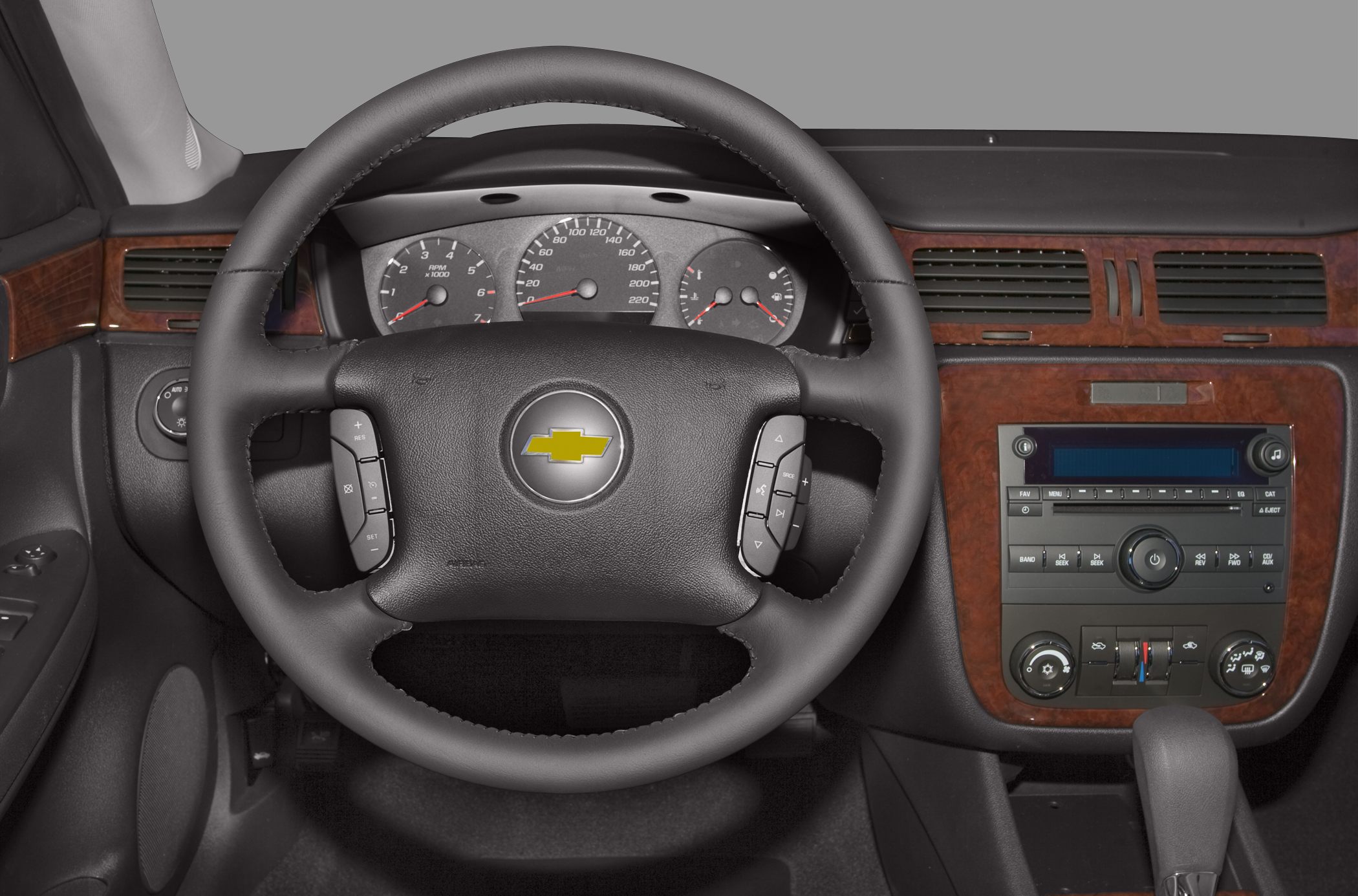 Steering wheel with control buttons and wood-paneled dashboard