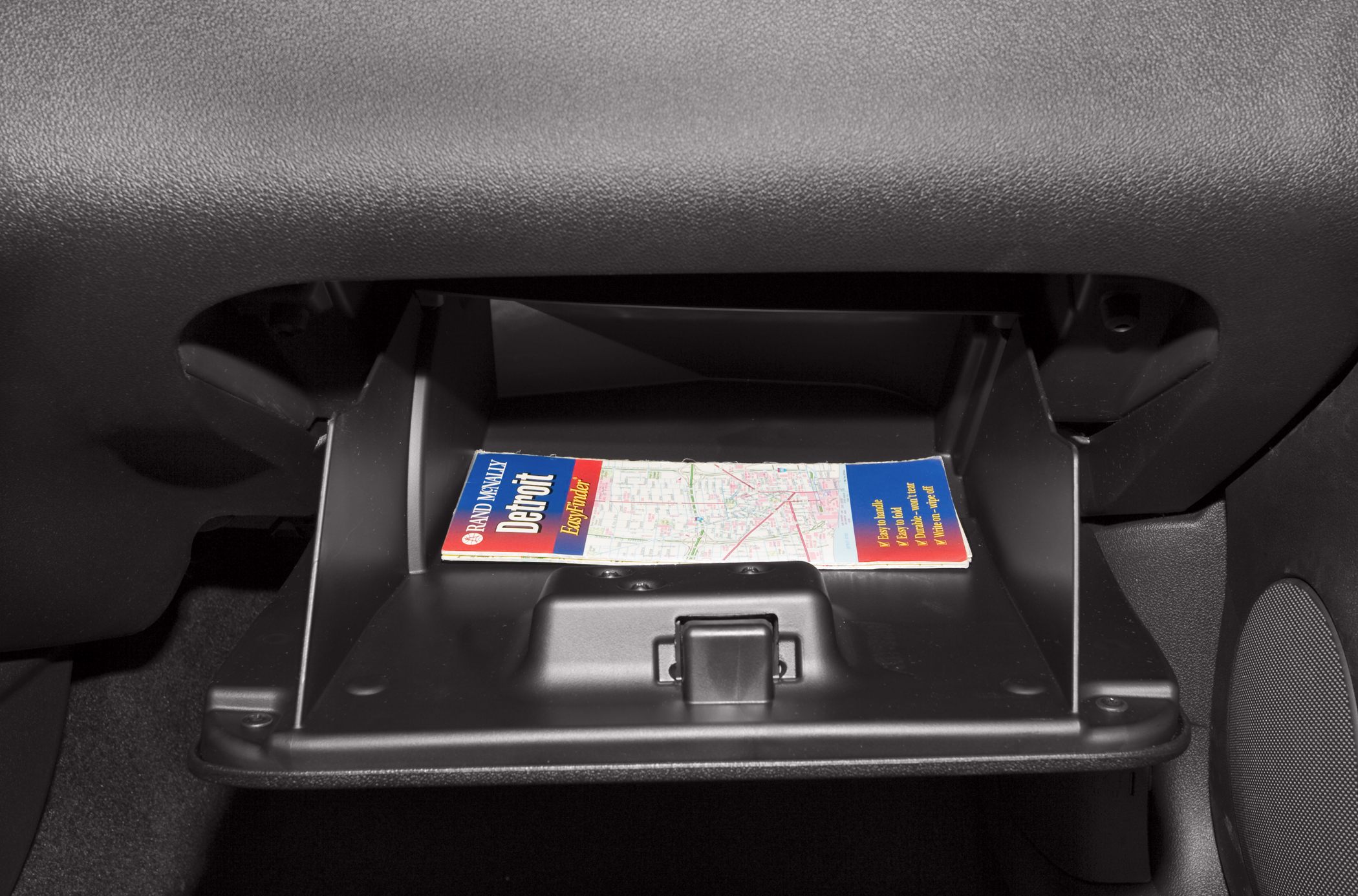 Open glove box with an inside storage compartment holding a map.