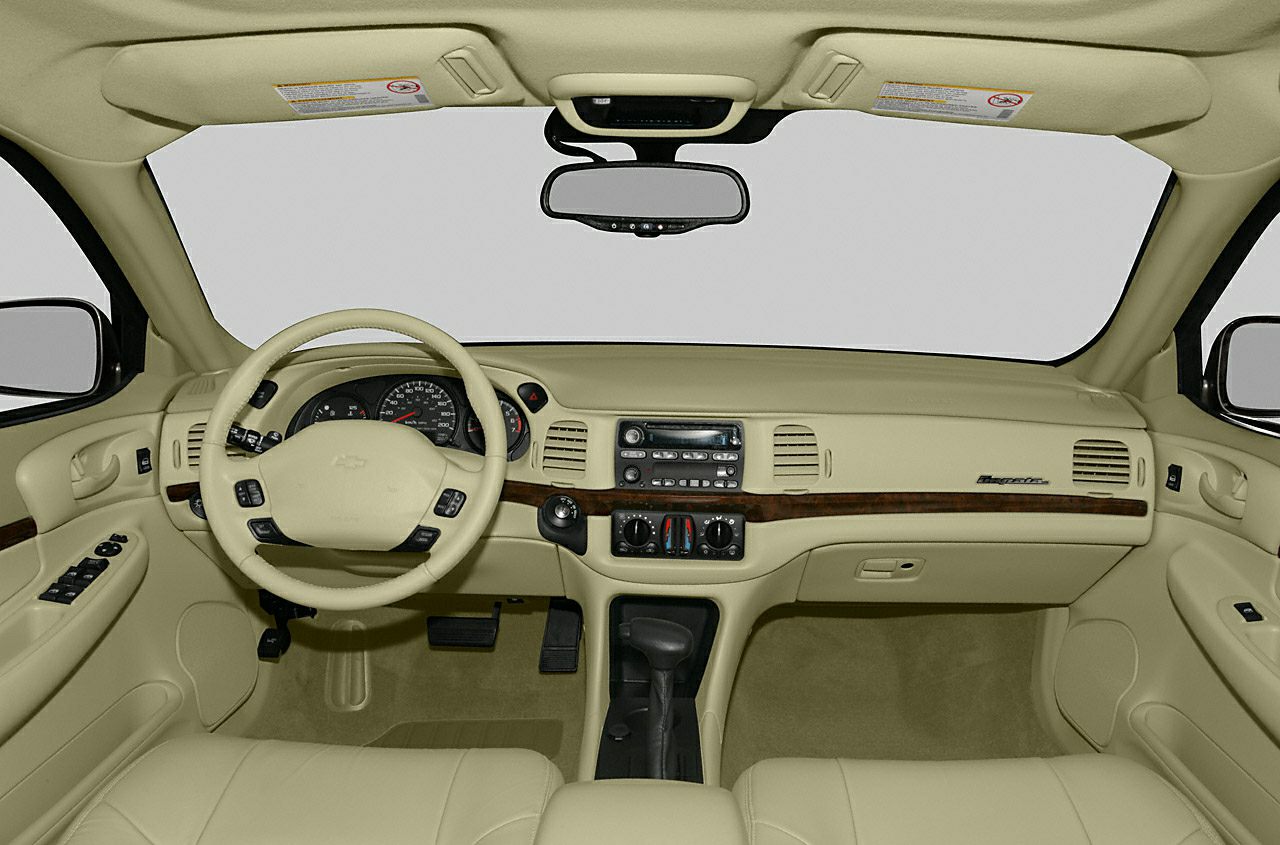 Beige car interior with dashboard, steering wheel, and wood trim