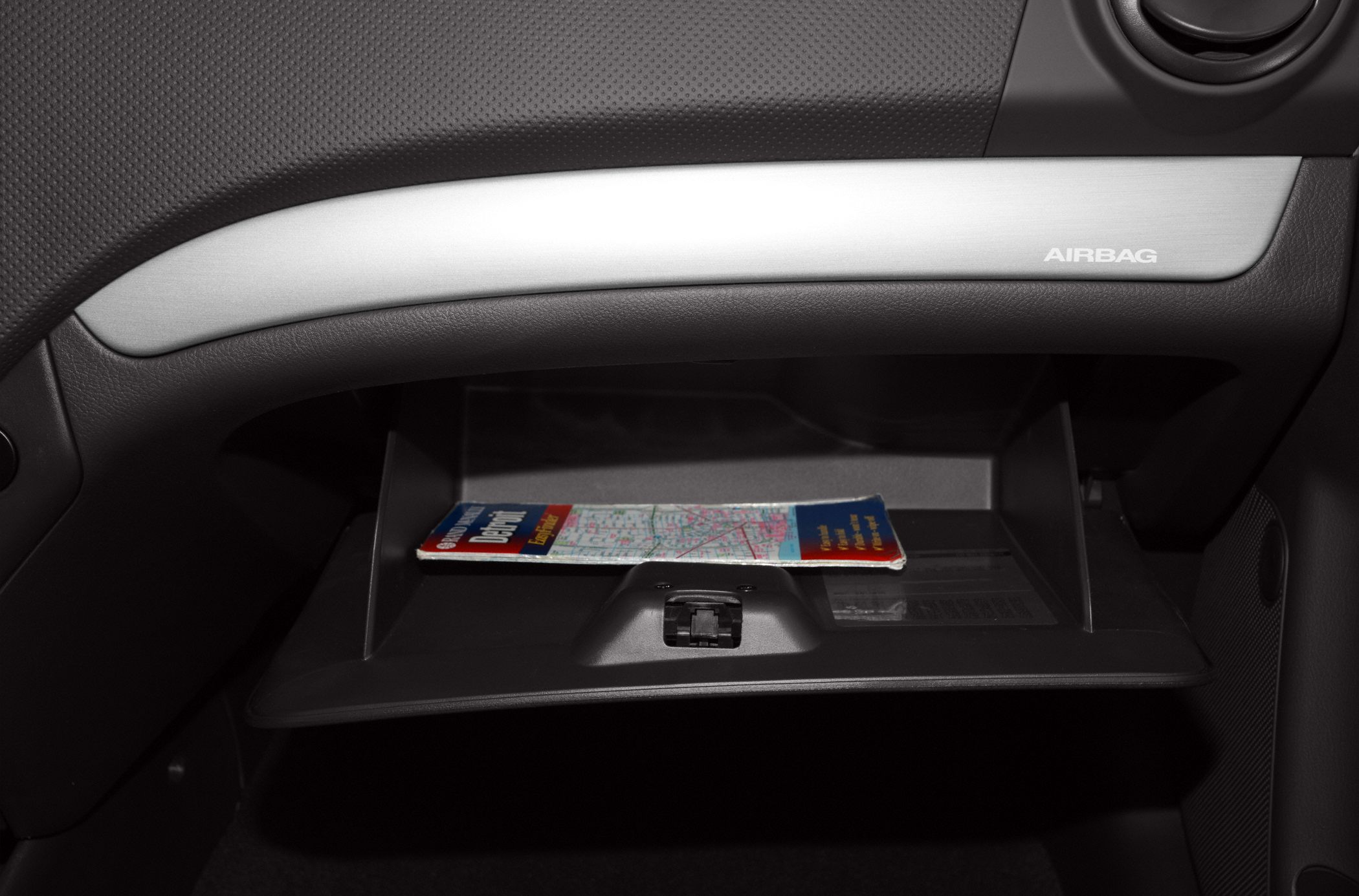 Open glove box with map and airbag label