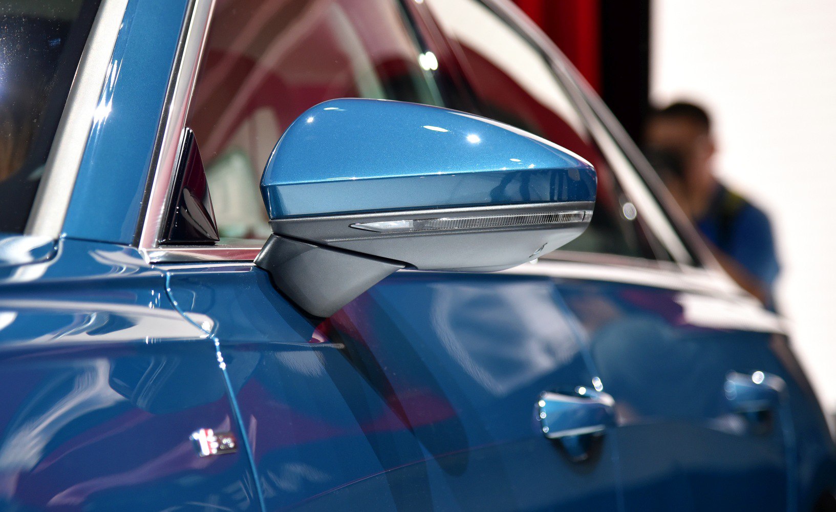 Blue side mirror with integrated turn signal on car door.