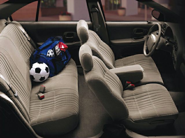 Front bucket seats and rear bench seating with sports gear inside.