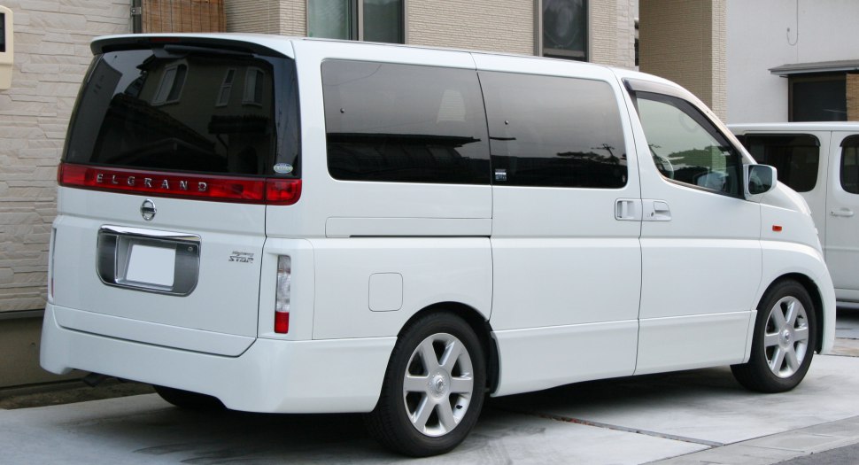 Rear side of white minivan with sliding door and vertical taillights.