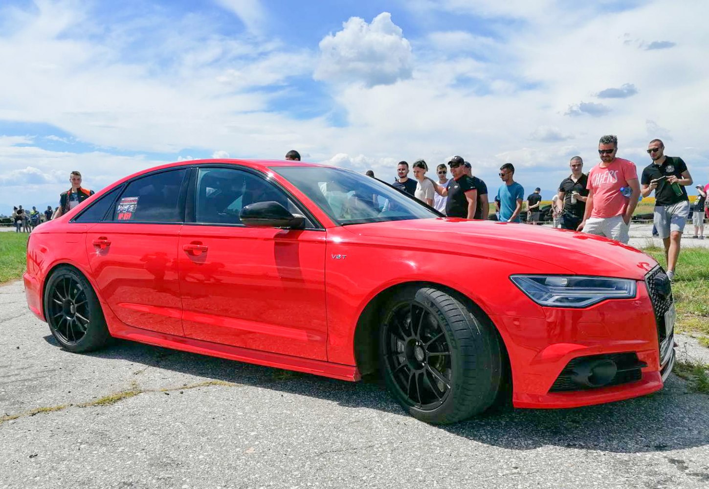 Red sedan with black multi-spoke wheels and V8 T badge.