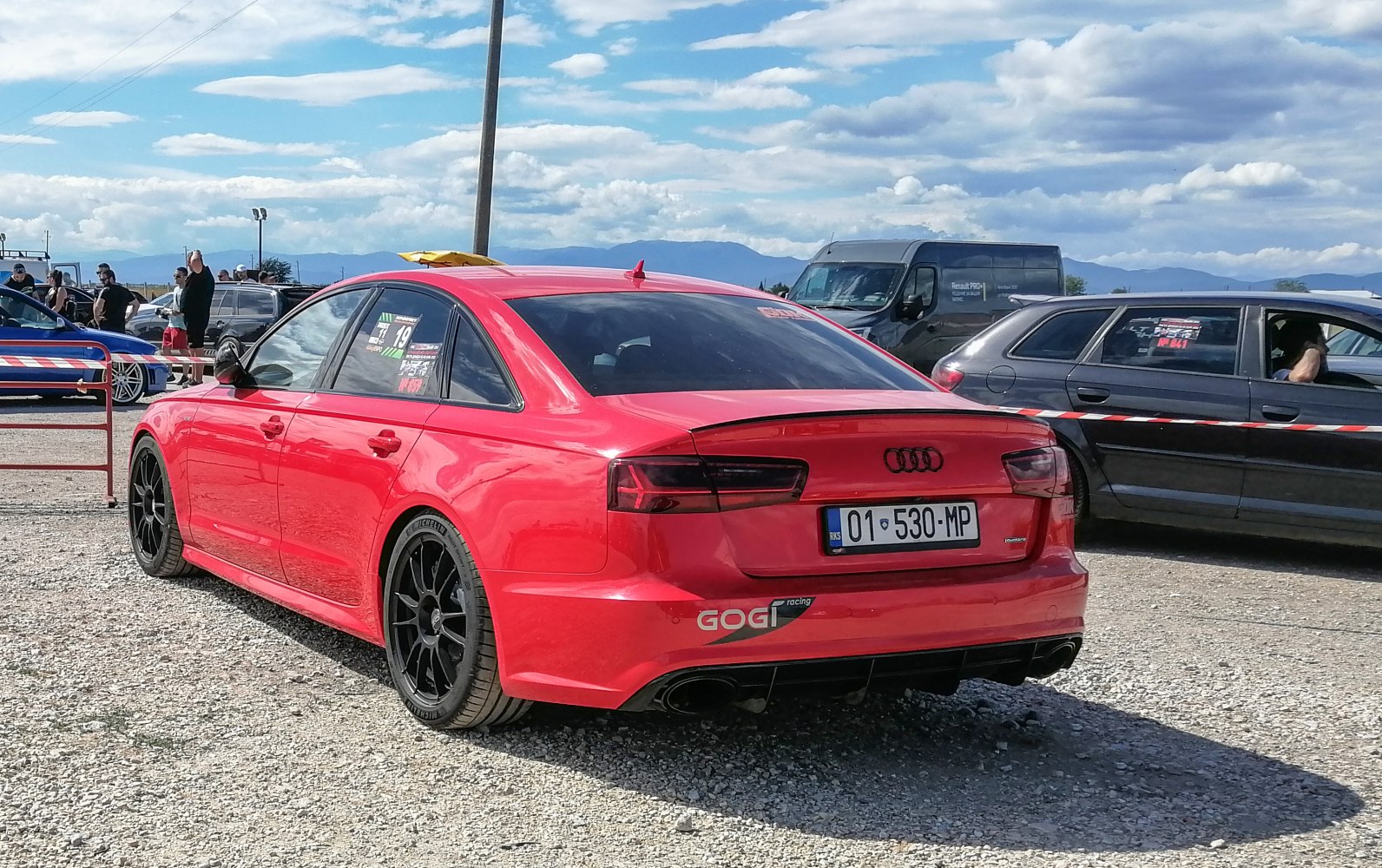 Red sedan with black alloy wheels and sporty rear diffuser