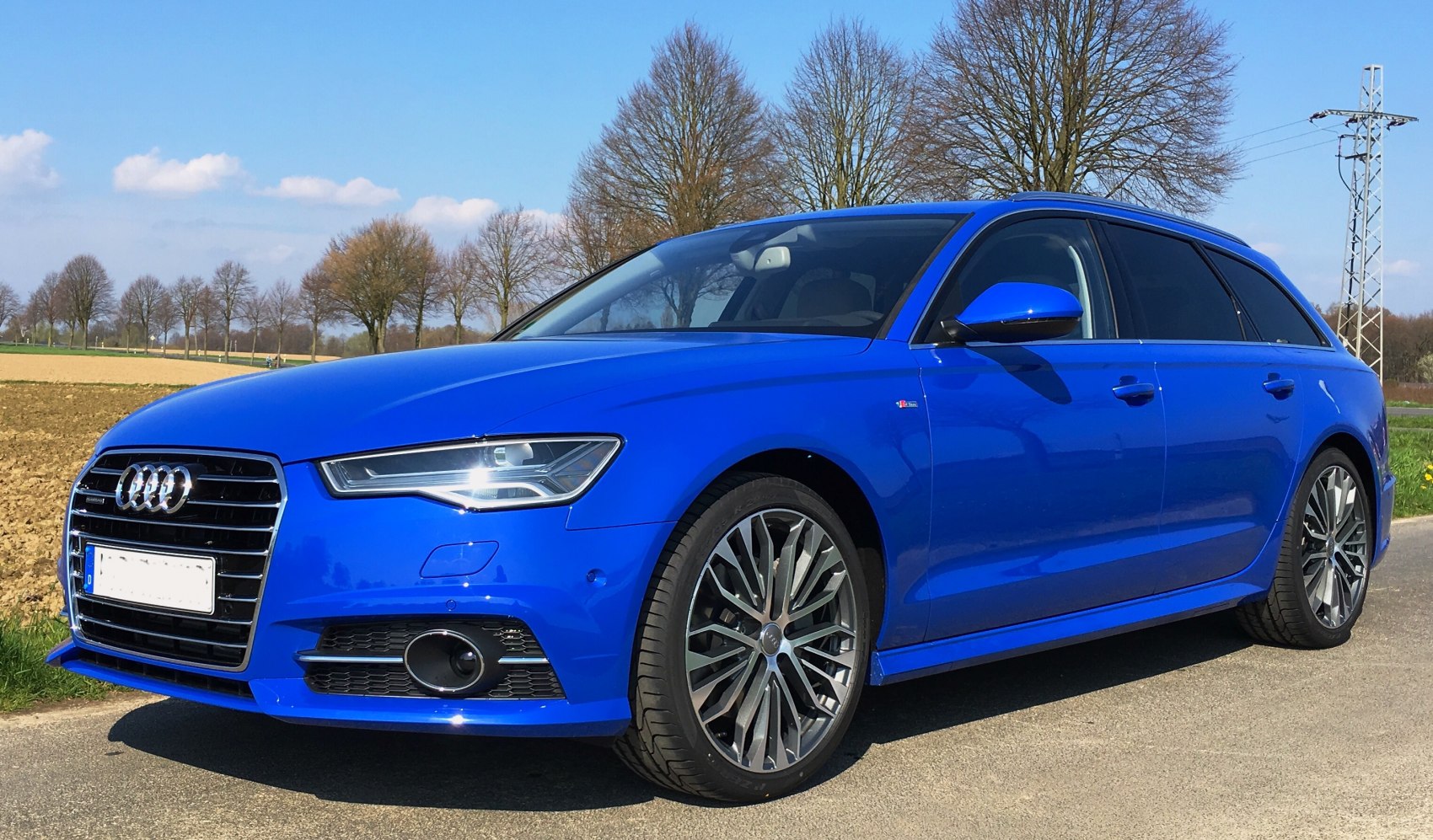 Front side view of a sleek estate with sporty alloy wheels and sharp headlights