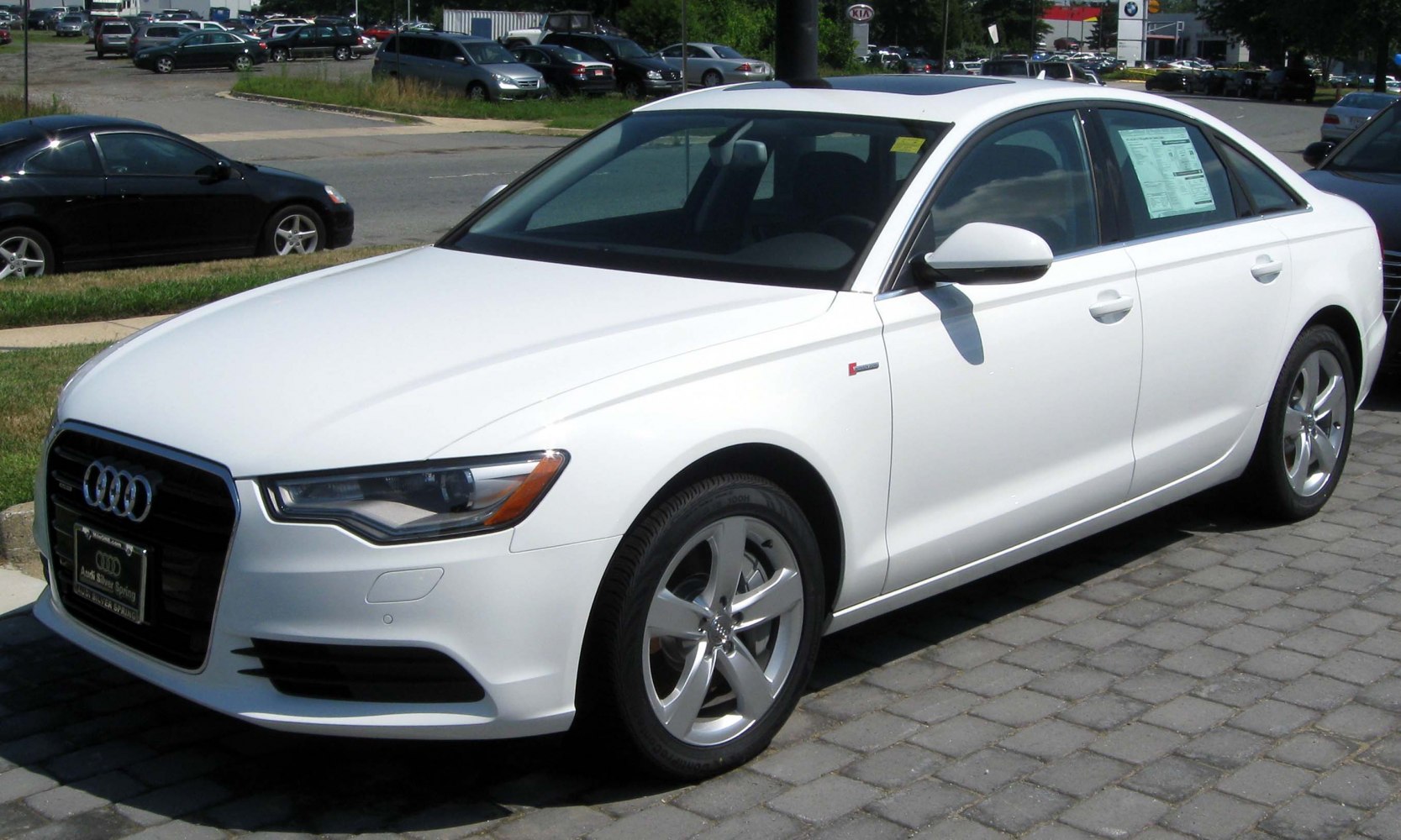 Front side view of white sedan with LED headlights and alloy wheels