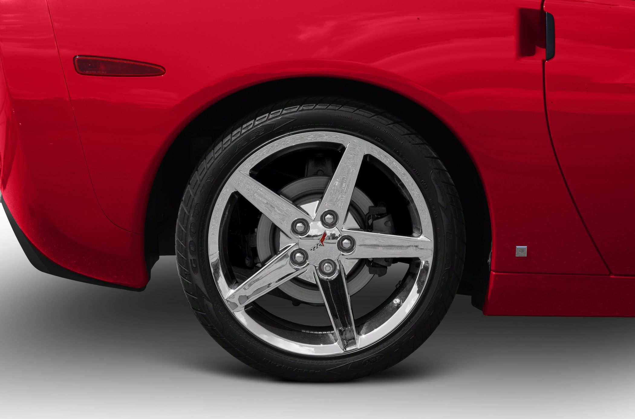 Chrome five-spoke wheel with racing emblem on red sports coupe