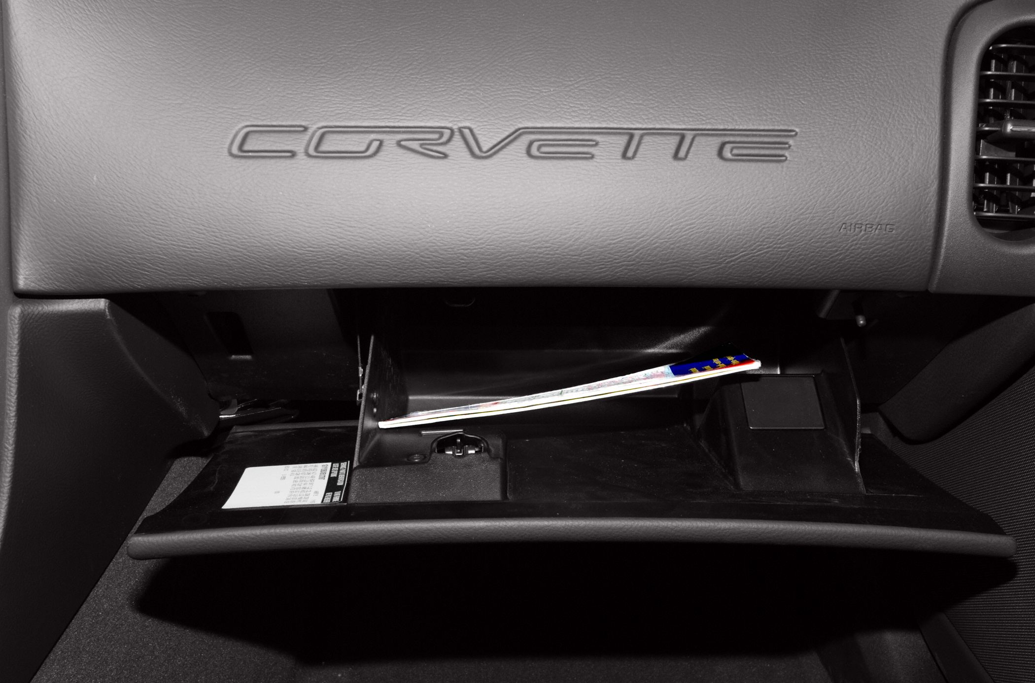 Close-up of Corvette glove box and embossed logo on dashboard leather