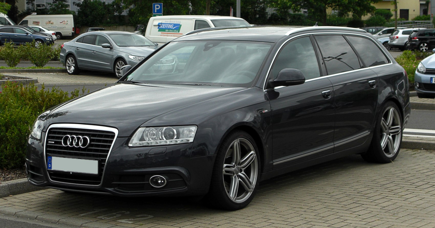 Front-side view of dark station wagon with sporty wheels and distinctive headlights.