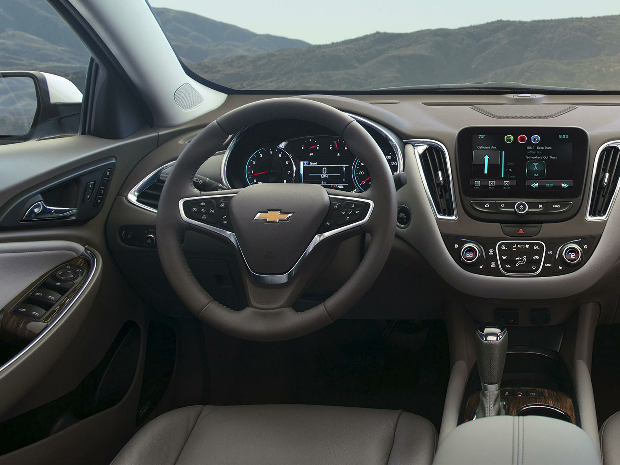 Steering wheel and dashboard with infotainment screen and controls.