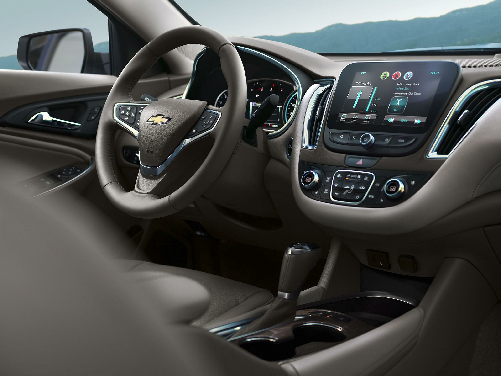 Touchscreen infotainment system and steering wheel with controls in car interior