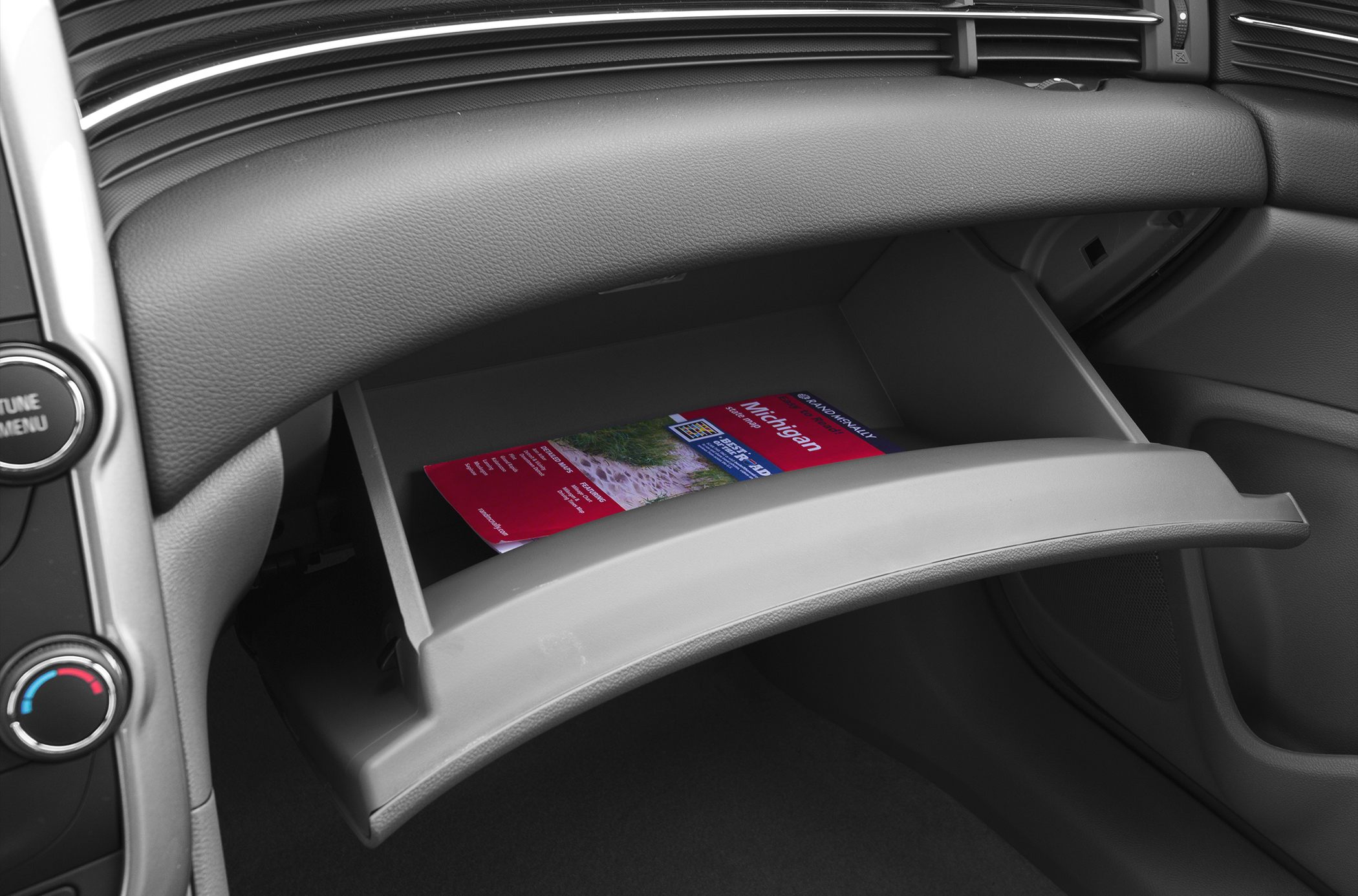 Open glove box with travel guide booklet inside car interior