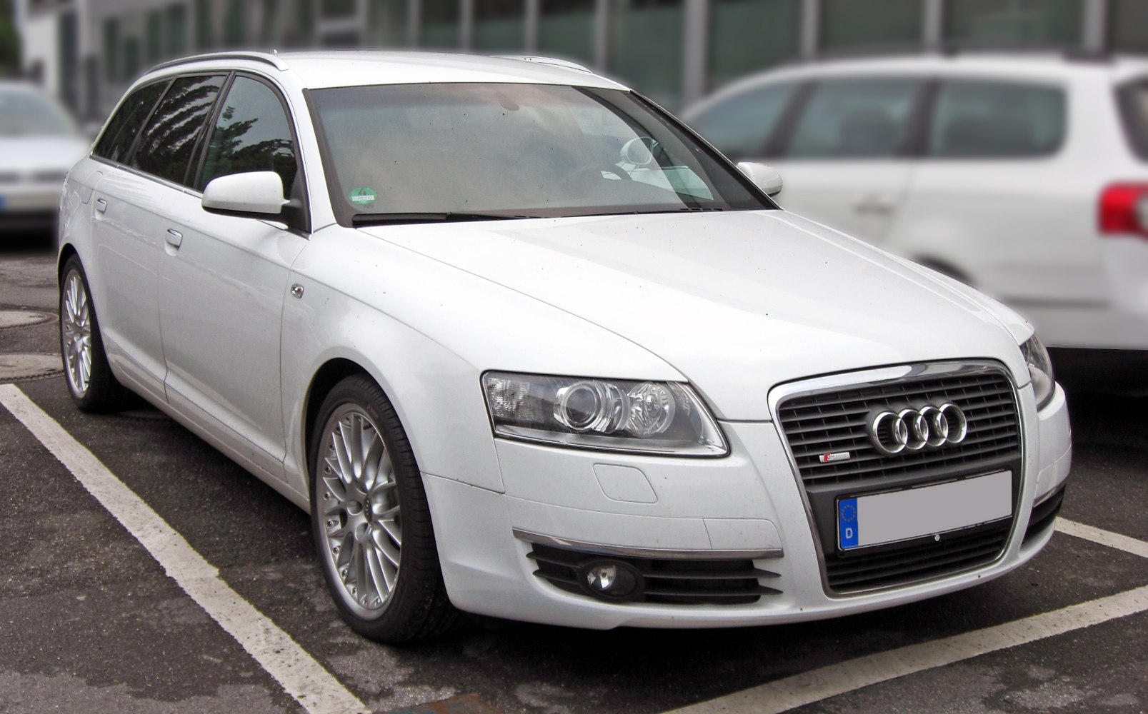 Front grille, headlights, and alloy wheels of a white station wagon.