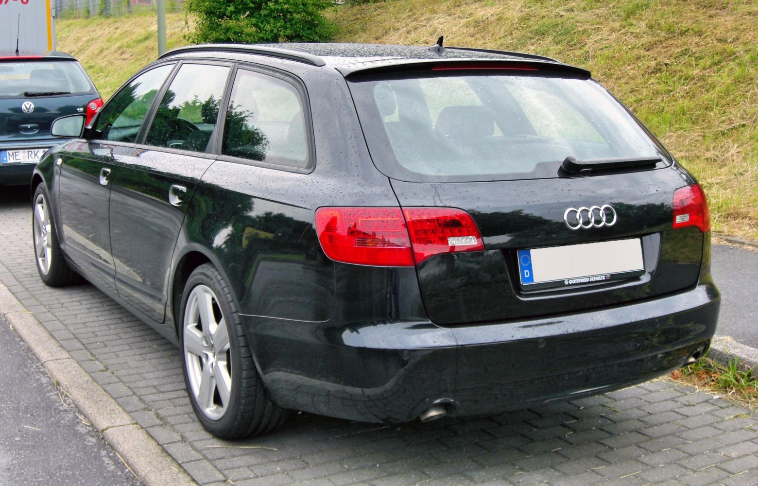 Rear view of a black station wagon with distinctive taillights and roof rails