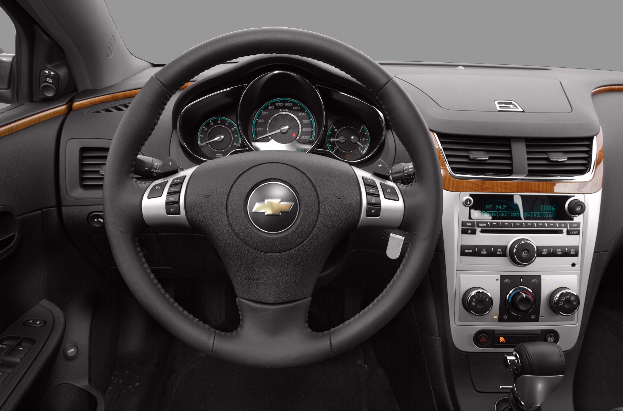 Leather-wrapped steering wheel and modern dashboard with wood trim.