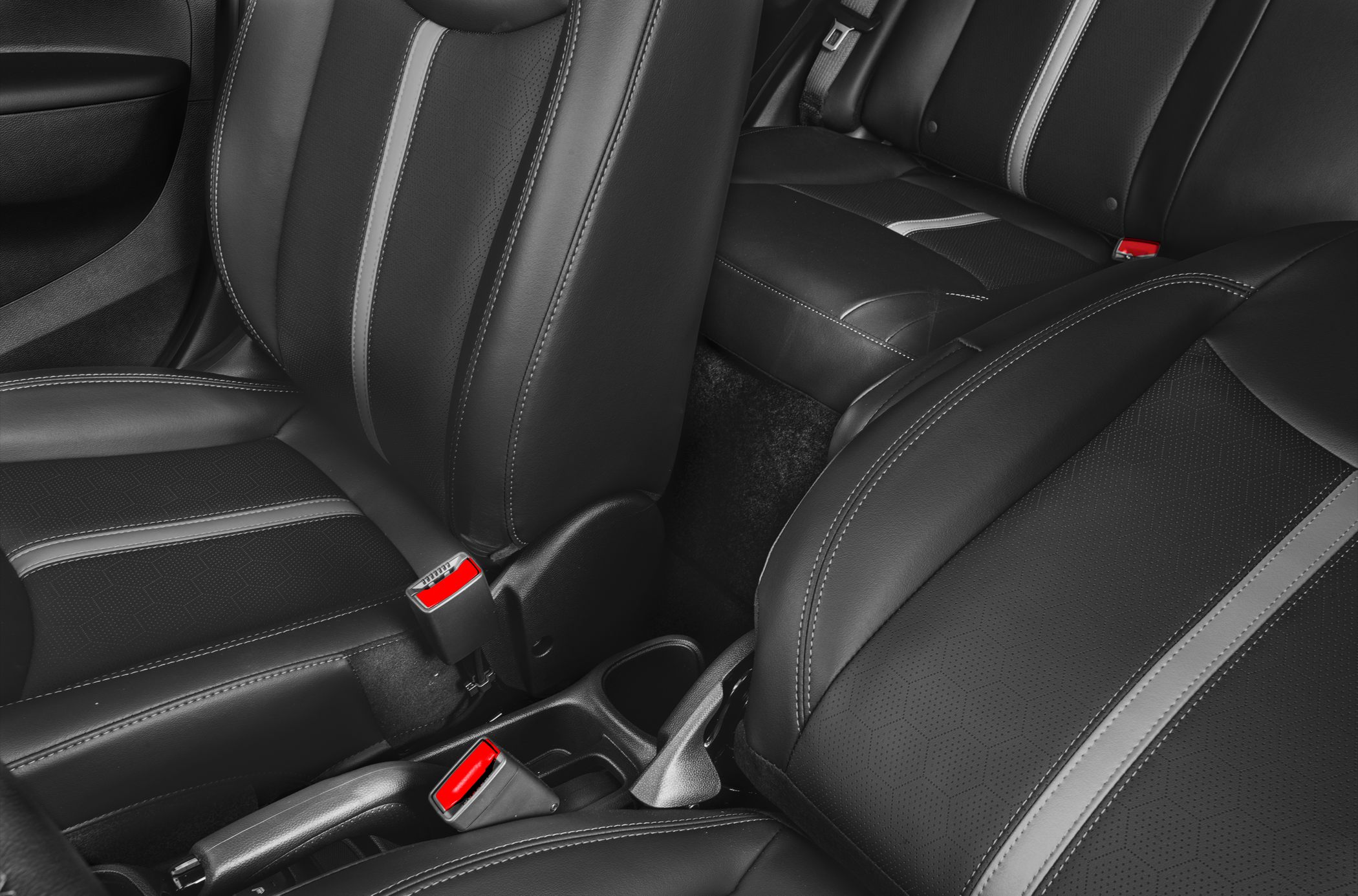 Close-up of black leather seats with patterned inserts and red seat belt latches