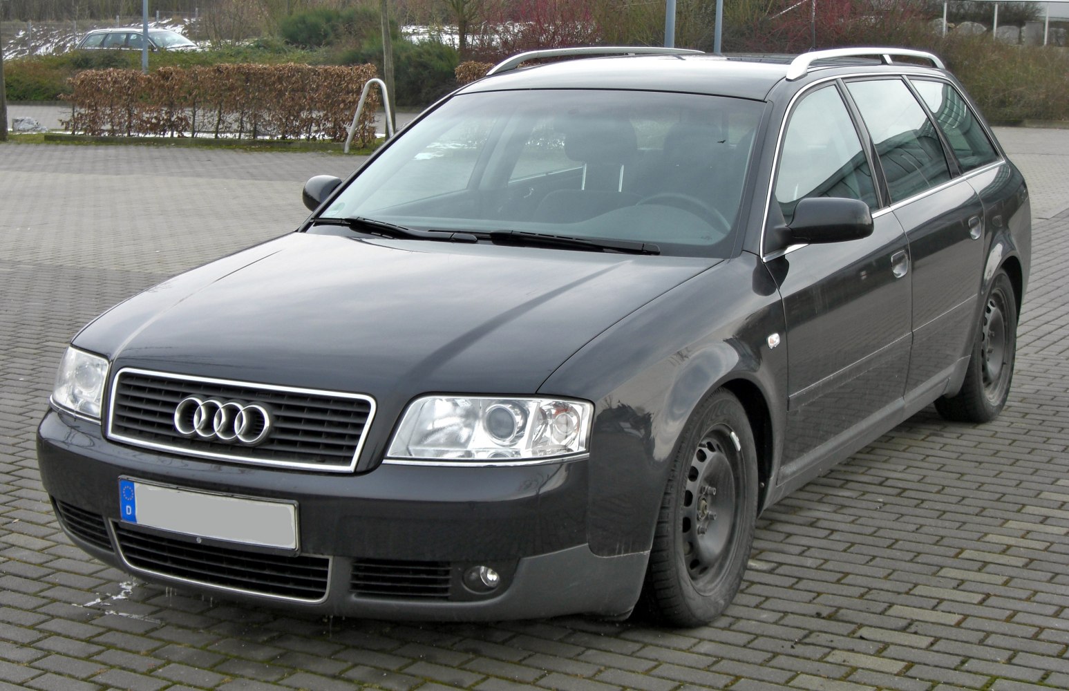 Front-side view of black estate car with grille and roof rails