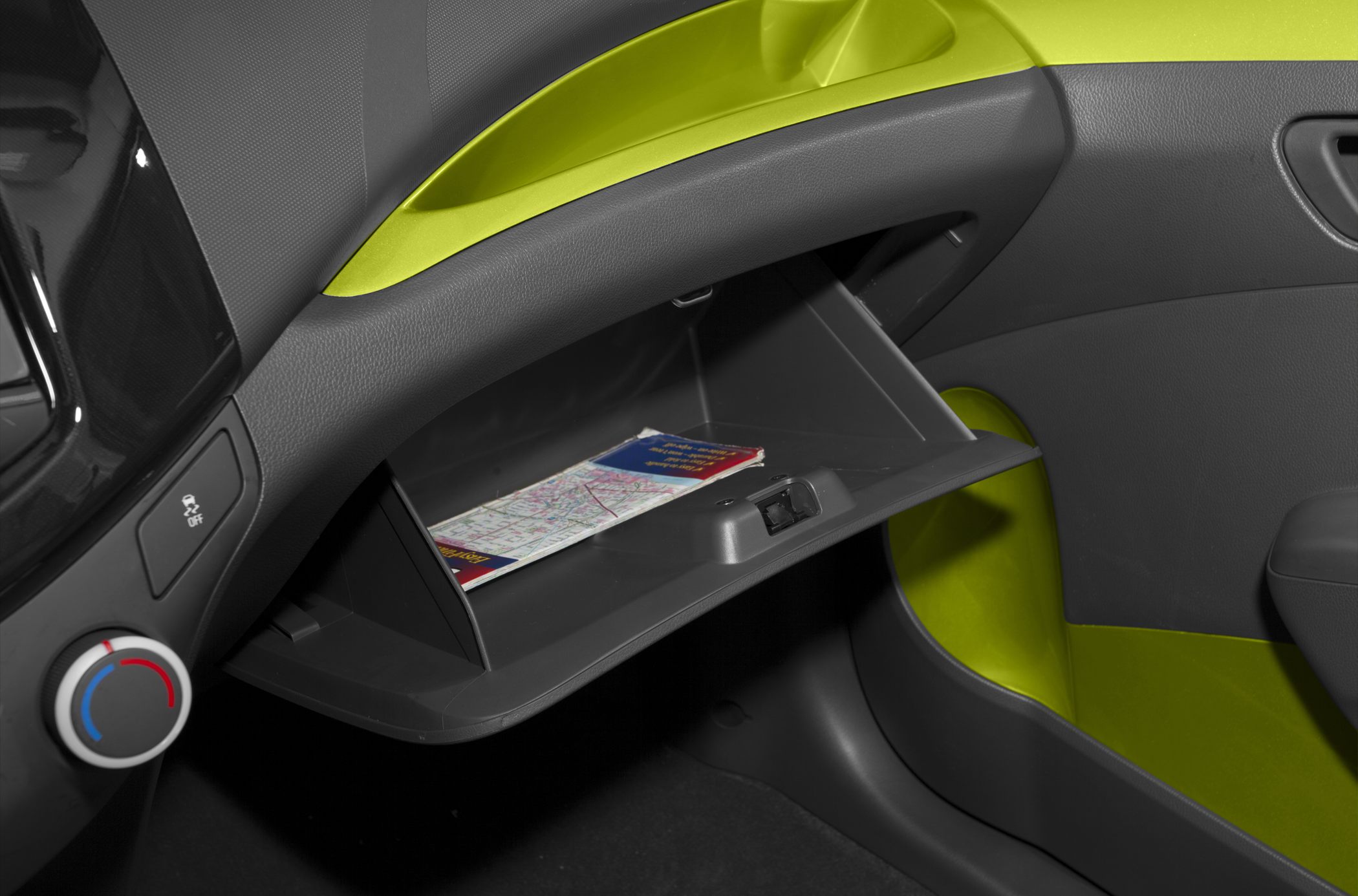 Open glove box with map inside, dashboard and control knob visible