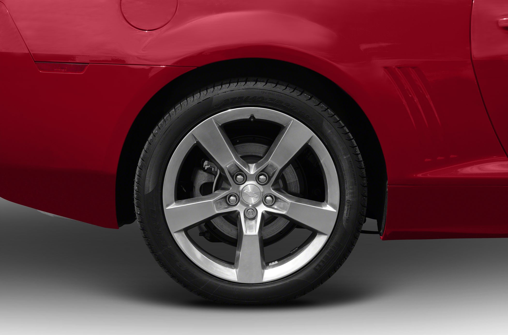 Rear wheel and fender detail of a red vehicle with alloy rim and side panel vents