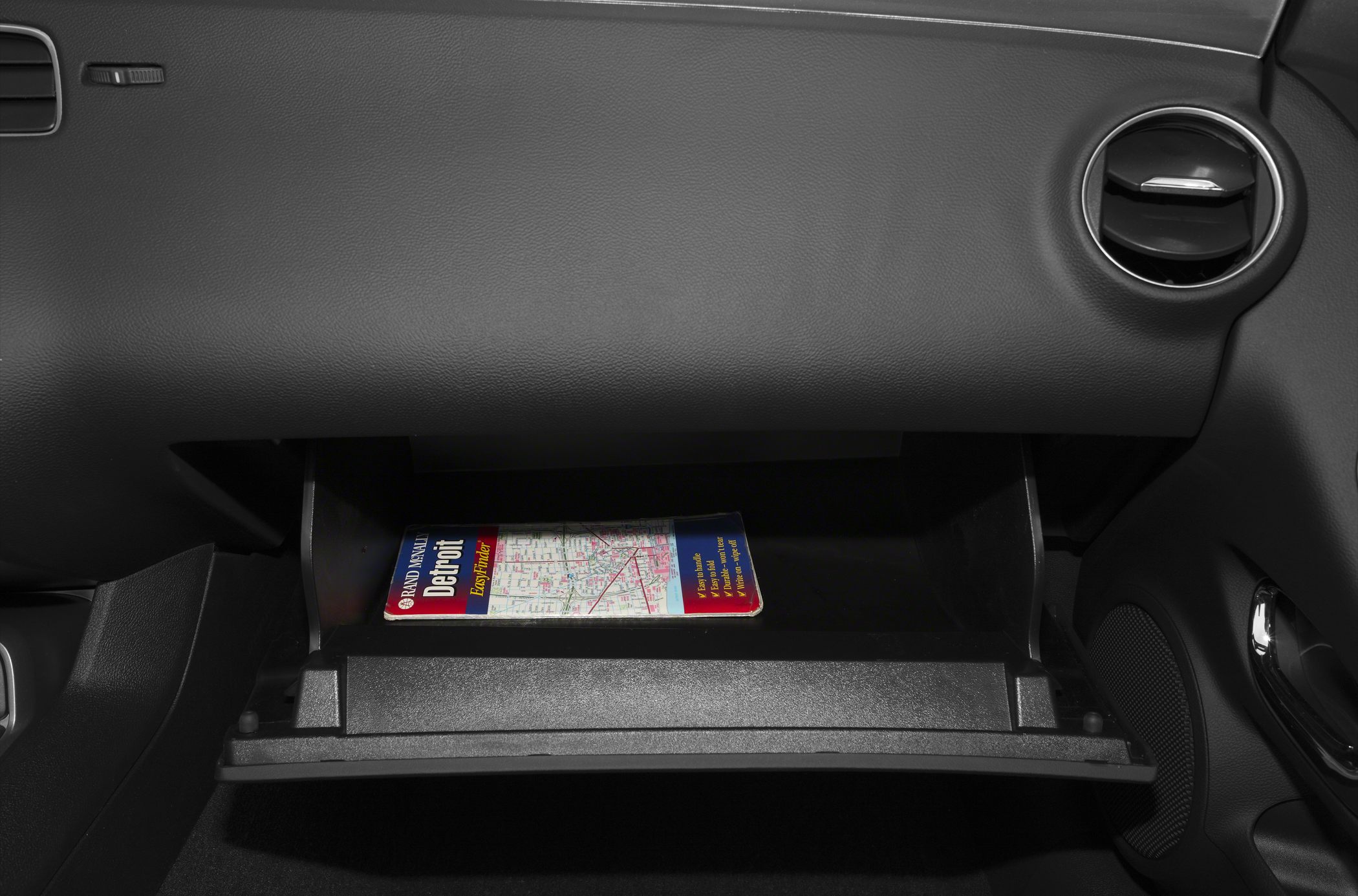 Open glovebox with map inside and circular air vent