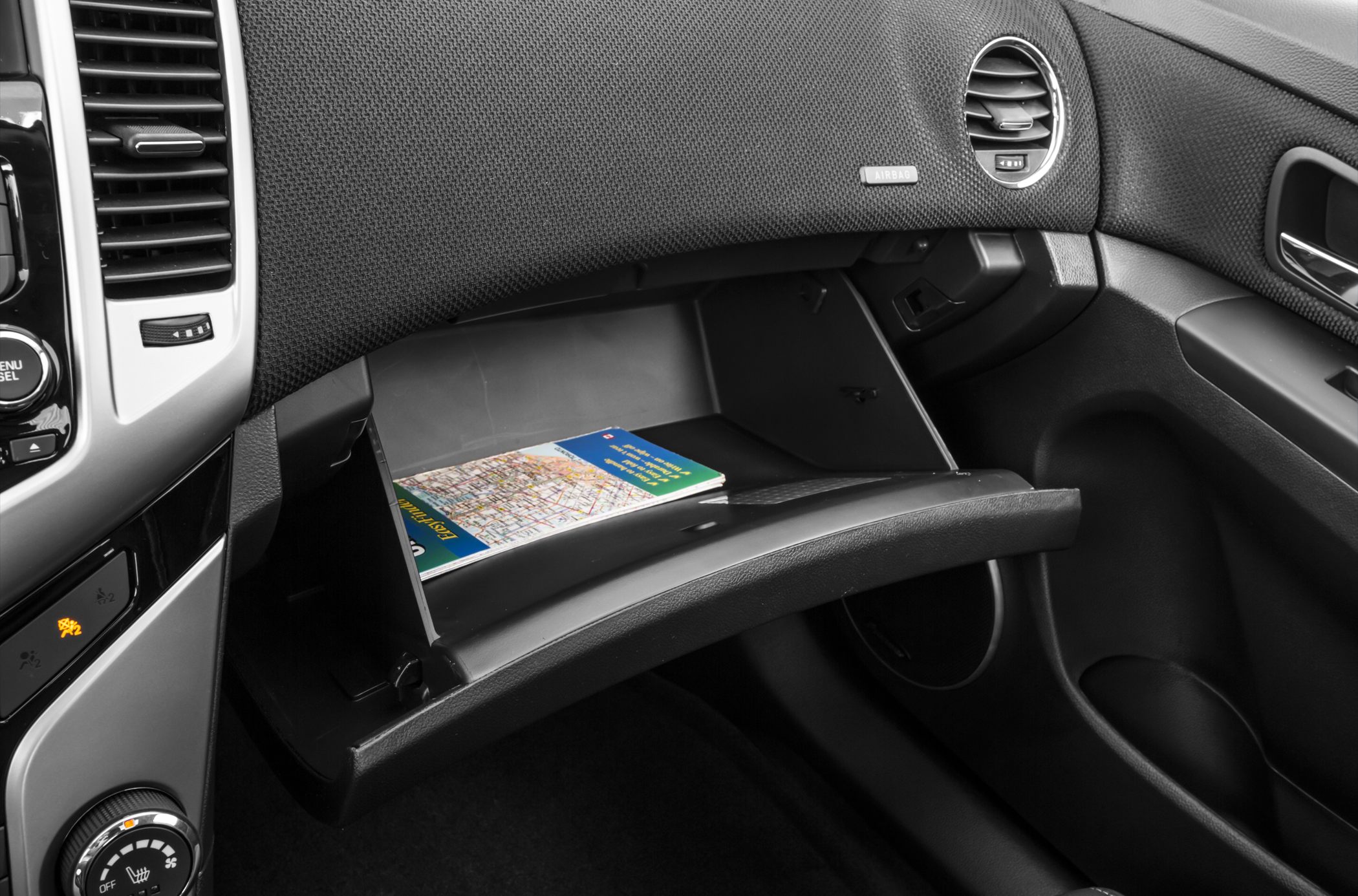 Open glove compartment with dashboard air vents and controls