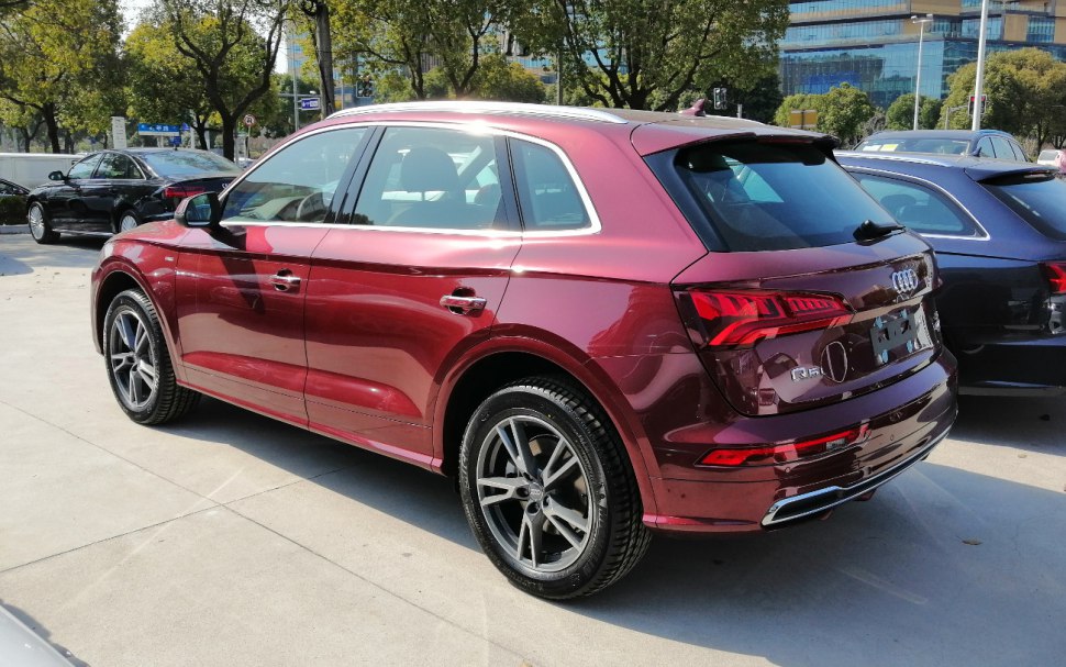 Rear side view of metallic red SUV with sleek roofline and alloy wheels