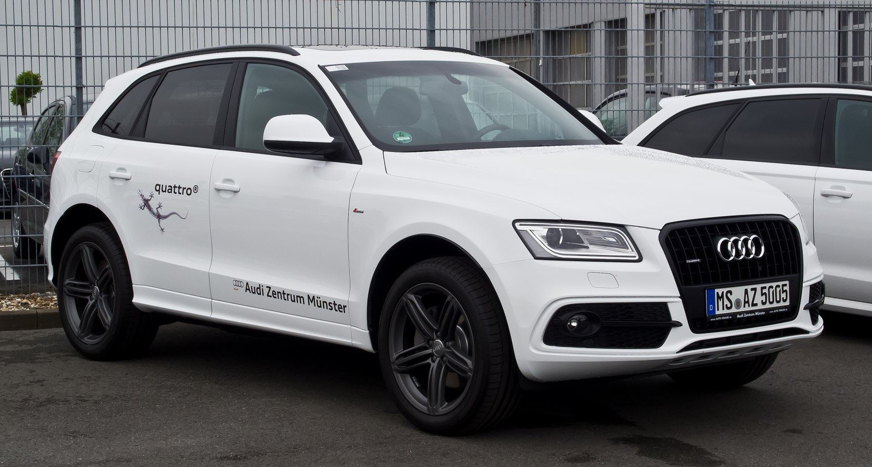 White SUV with quattro AWD and black sporty rims from front-side view.