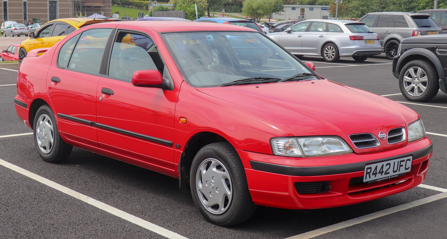 Red sedan with signature front grille and classic alloy wheels.