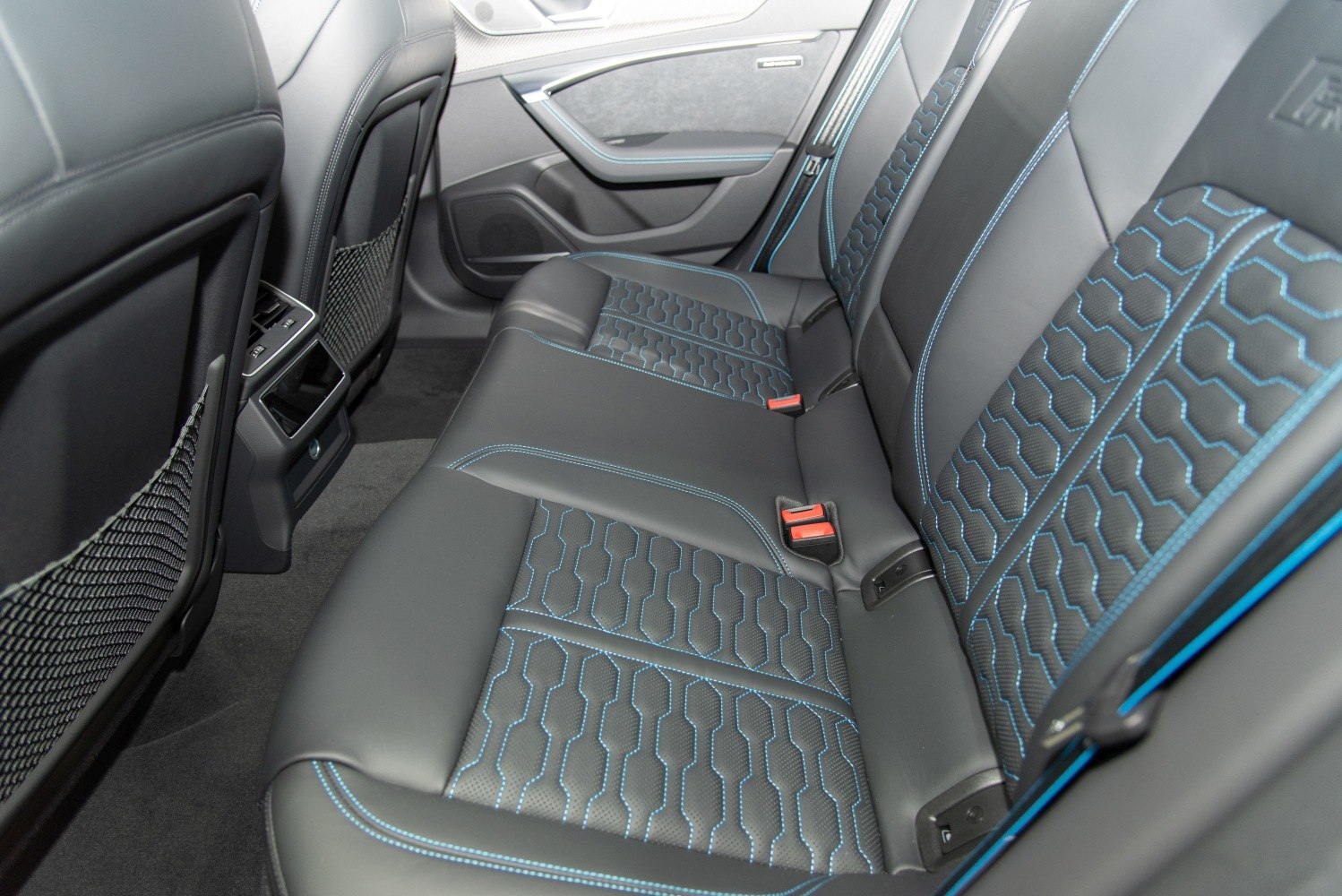 Rear perforated leather seats with blue contrast stitching and unique pattern.