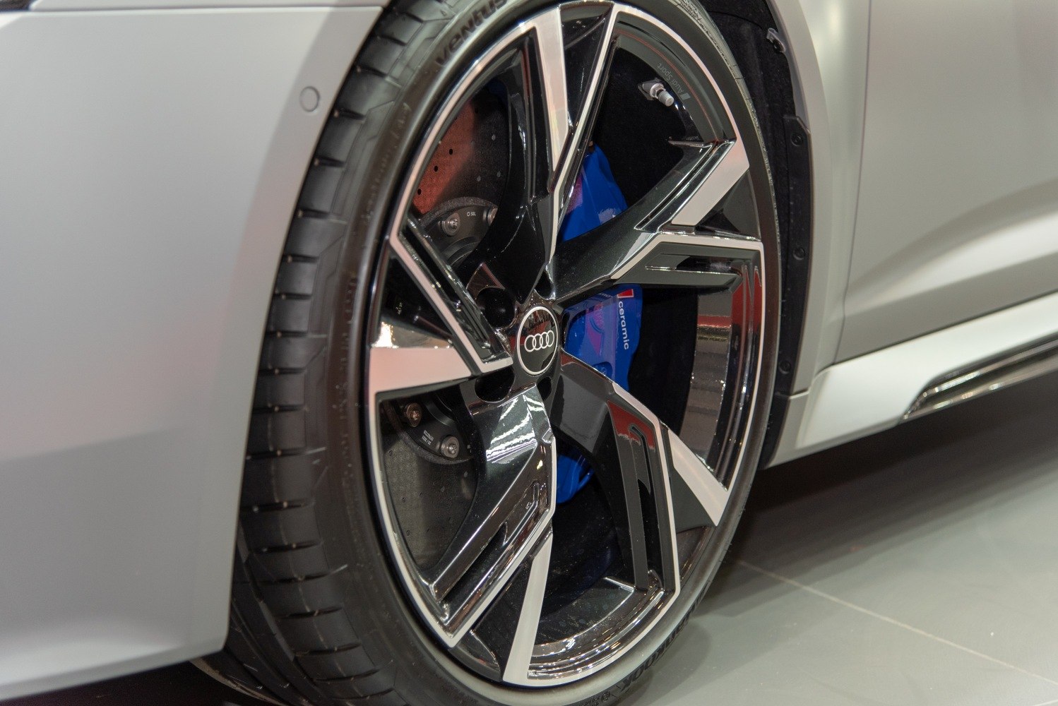 Close-up of high-performance alloy wheel and blue ceramic brake caliper