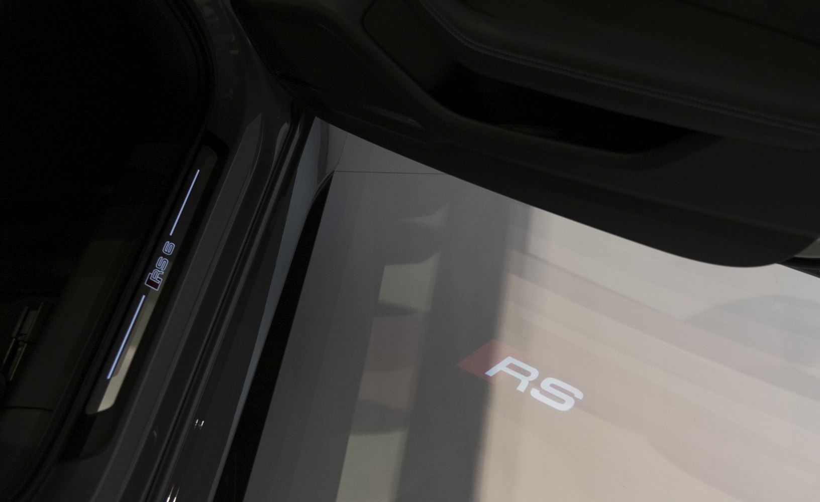 Illuminated door sill with RS 6 logo and RS badge projection inside car door.