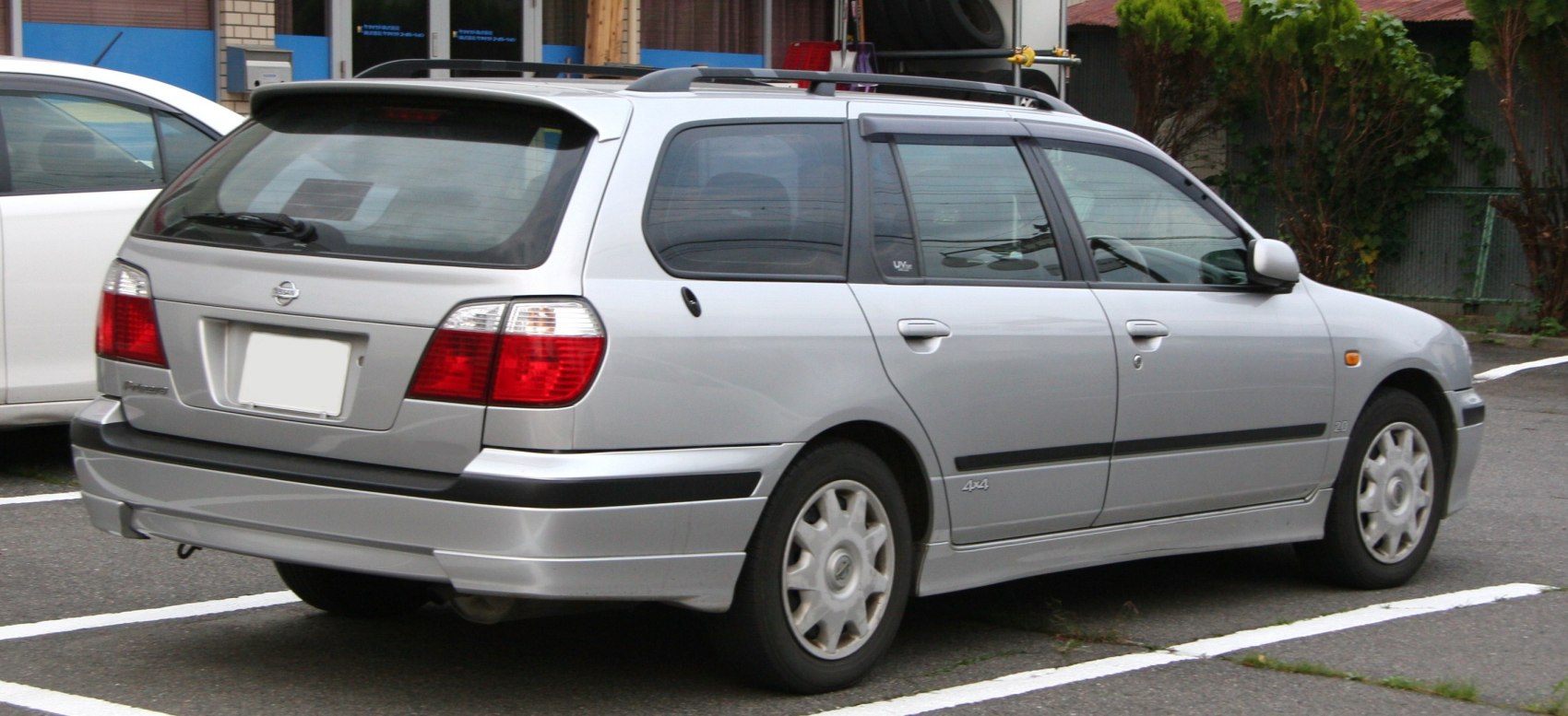 Rear side view of silver station wagon with 4x4 badge and roof rails