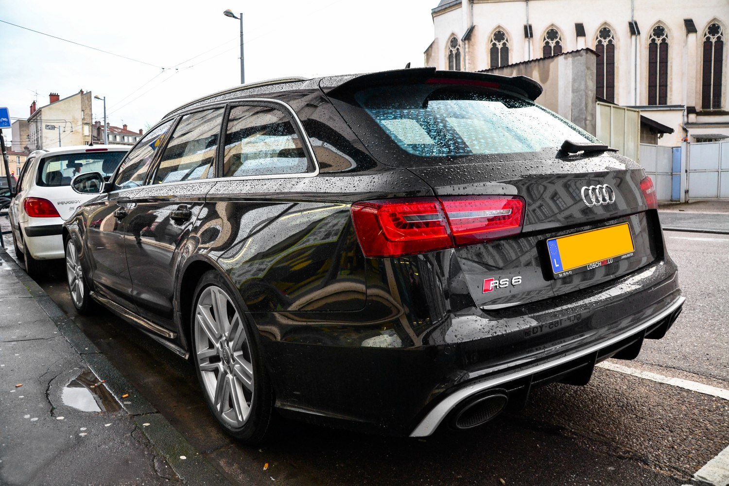 Rear-side view of black Audi RS6 Avant with distinct taillights and silver wheels