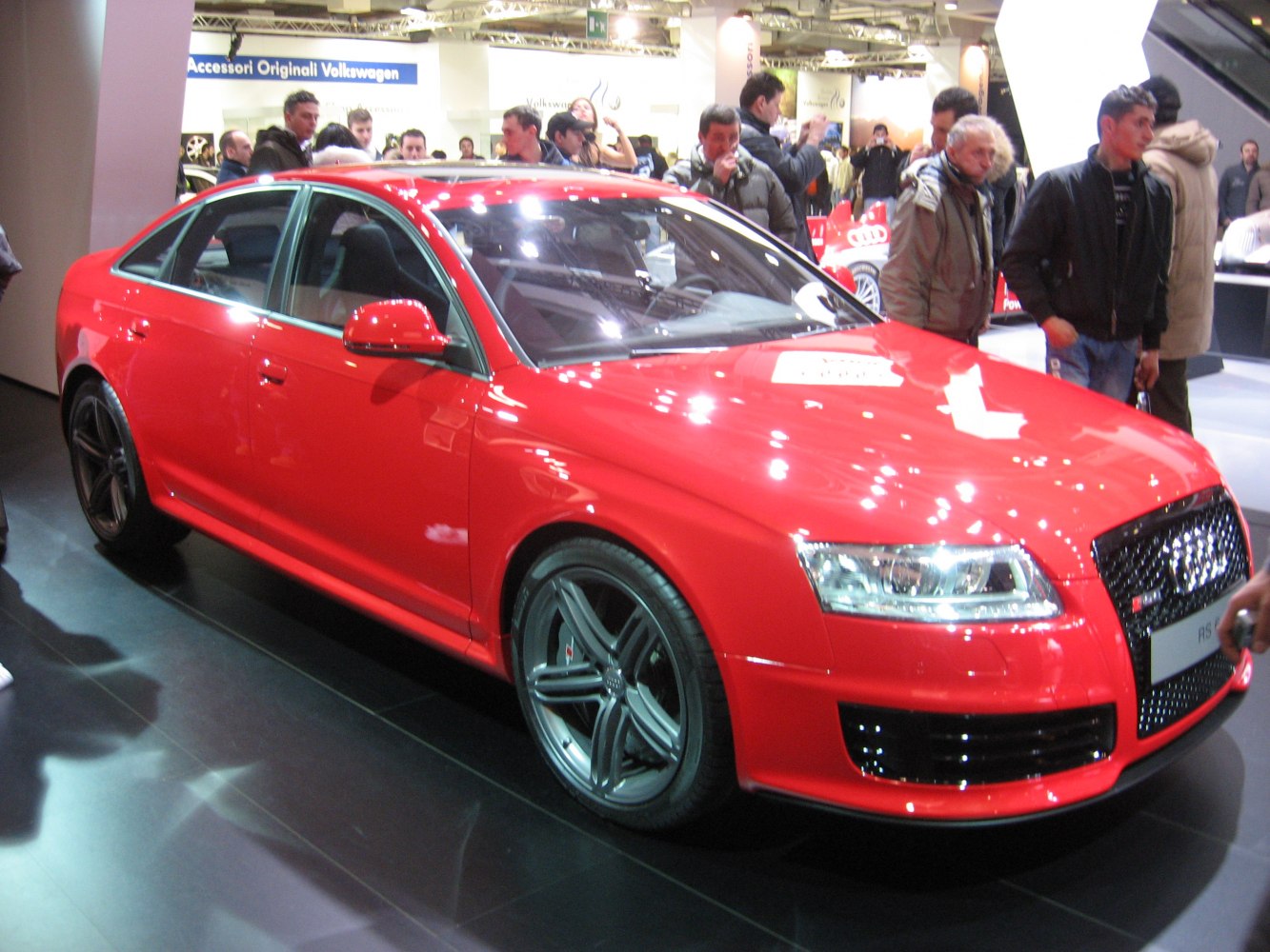 Red sporty sedan with black five-spoke alloy wheels and aggressive front grille