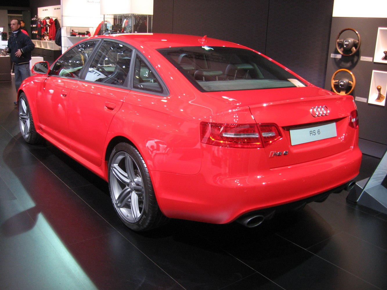 Rear side view of red sporty sedan with dual exhaust and alloy wheels