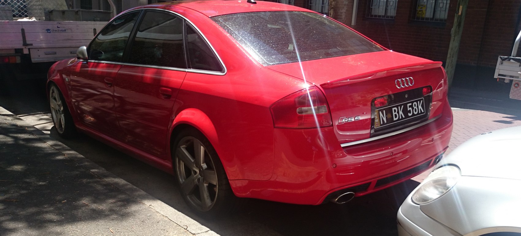 Red sedan with sporty alloy wheels and tinted windows from rear-side view