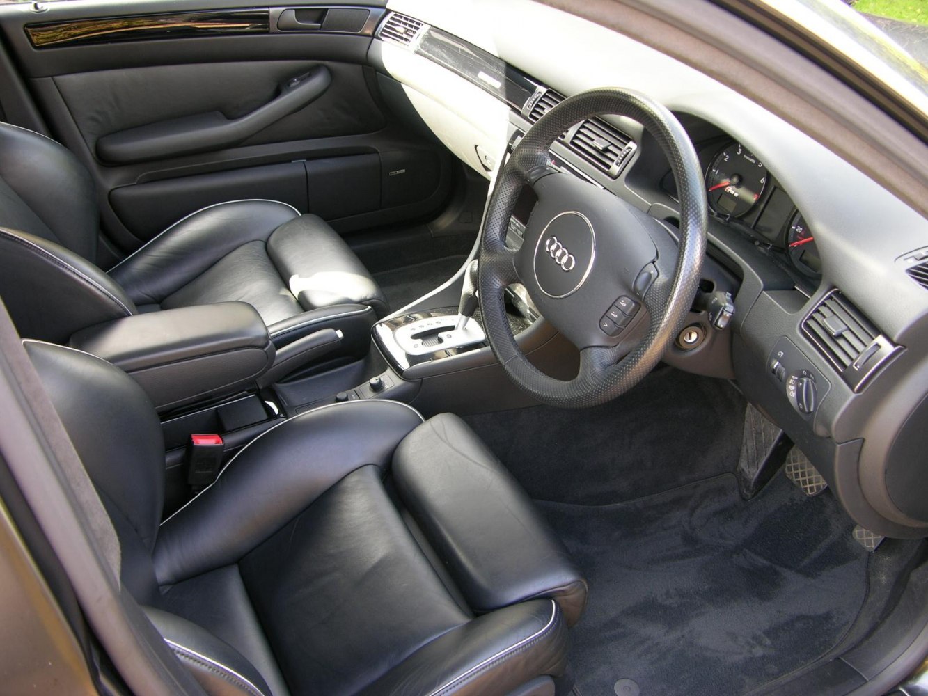 Black leather seats and sporty Audi steering wheel inside a car.