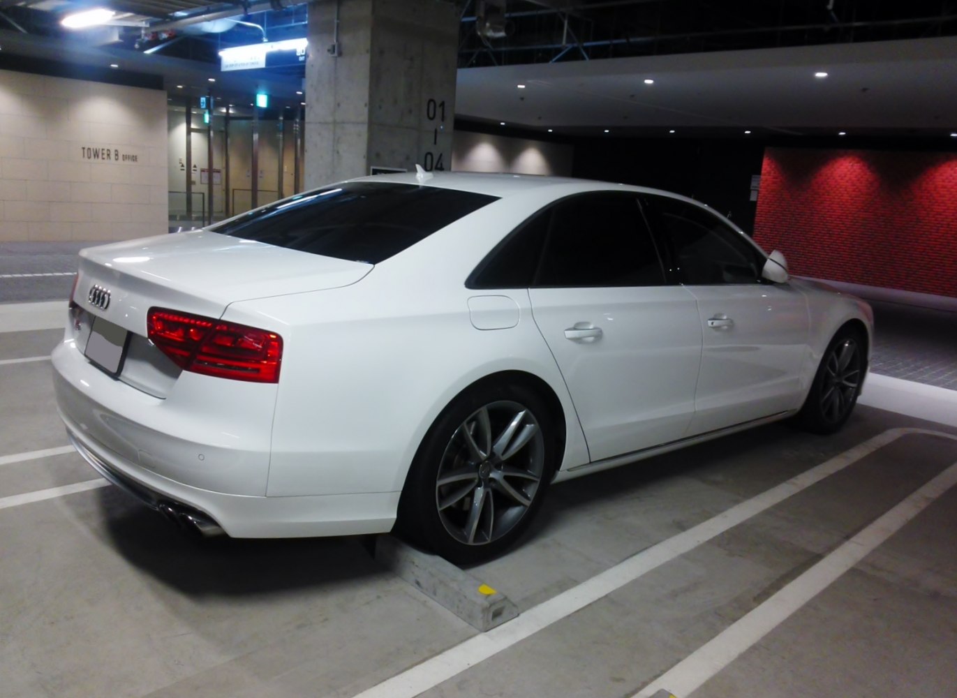 Rear and side view of white luxury sedan with tinted windows and alloy wheels